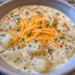 Pot of golden cheesy potato soup with herbs and garlic
