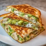 Golden, crispy chicken avocado quesadillas cut into wedges on a plate