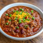 Bowl of Texas Roadhouse copycat chili topped with shredded cheese and green onions.