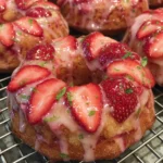 Plate of pink glazed strawberry cake donuts with fresh strawberries around